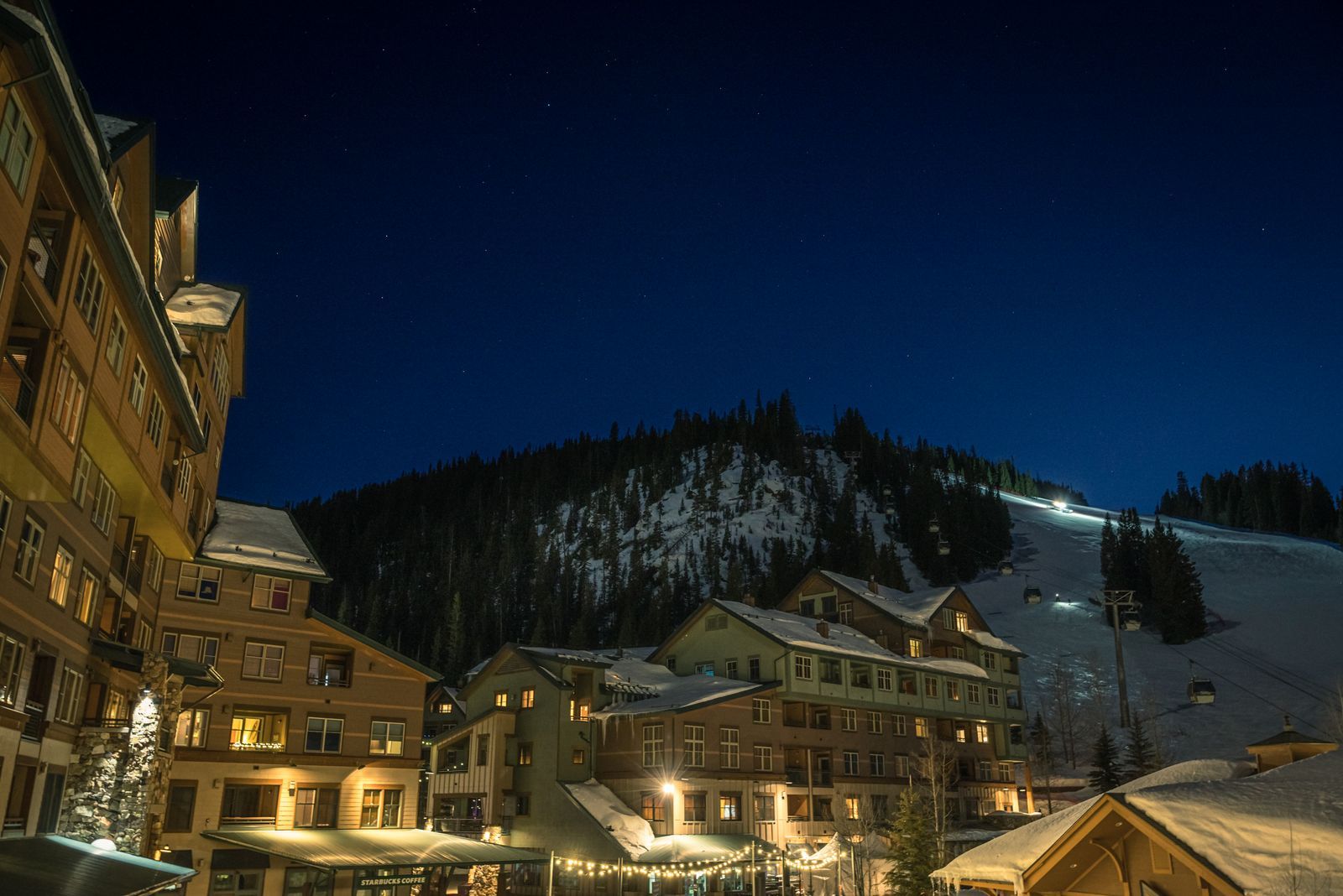 Station de ski illuminée la nuit au pied des montagnes enneigées